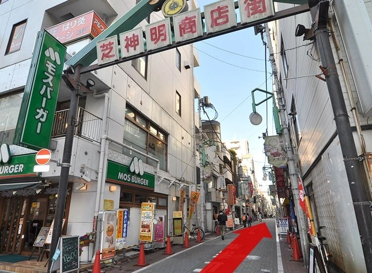 Walk past "Koshin Building" and several other buildings, and you will find a stone paved street with a sign above that says, "Shibashinmei Shopping Street (芝神明商店街)" on your right side. Enter this shopping street and walk straight for about four minutes. We are located on your left.