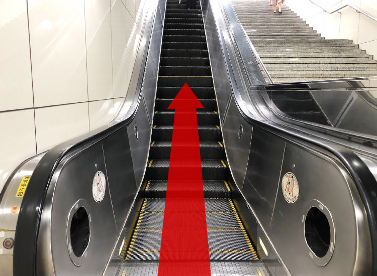 Go up the escalator and go to the ground level.