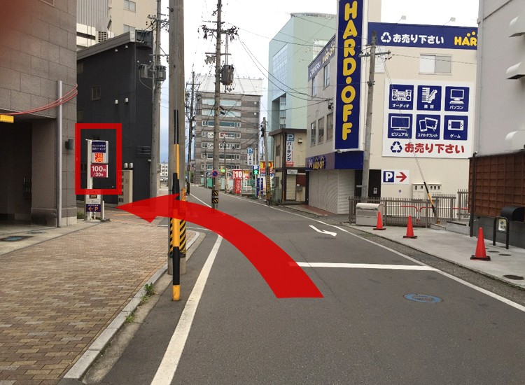 After turning left, you will see the signboard (indicated by the red frame) of our contract parking lot, West Plaza Nagano Parking, on the left side of the road that is about 10 meters from the intersection. Go to the alley beside the signboard. 