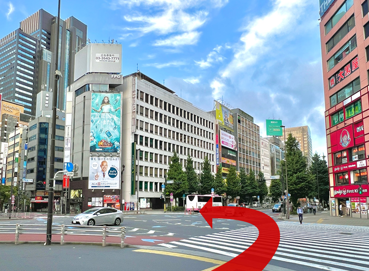 西新宿1丁目の交差点を矢印の通り、右に渡った後、さらに左に横断します。